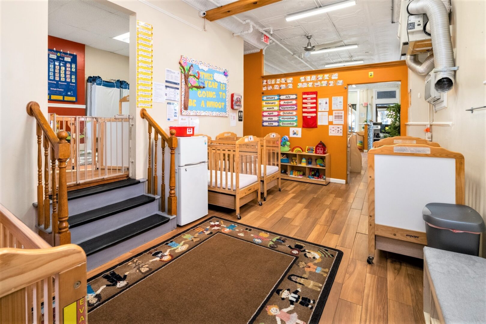 Infant room at Smart Start Academy with wooden cribs and gated stairway access