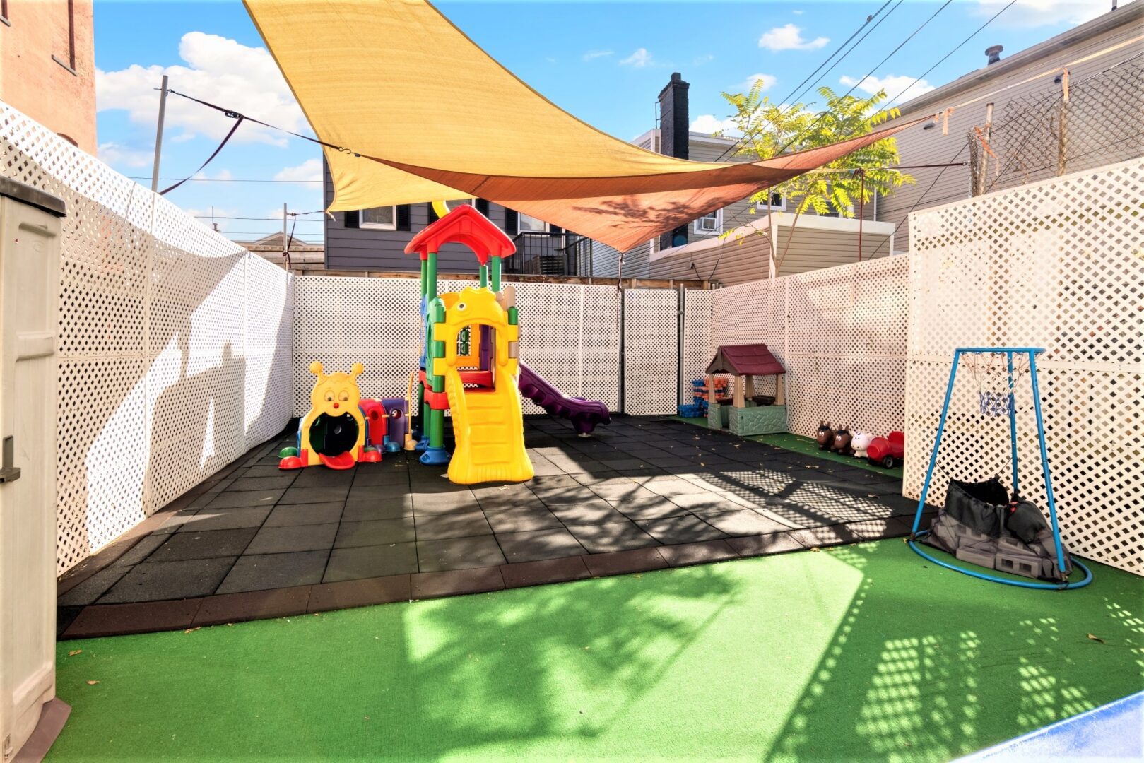 Shaded private playground at Smart Start Academy with slide, swing, and turf surface