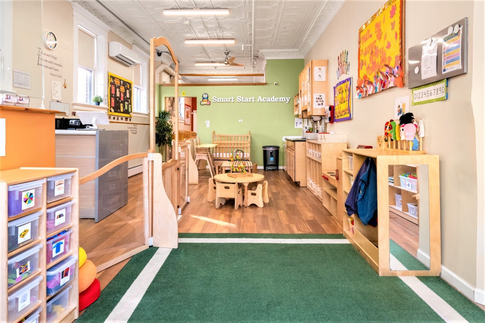 Gated toddler classroom at Smart Start Academy with low mirror and sorted activity bins