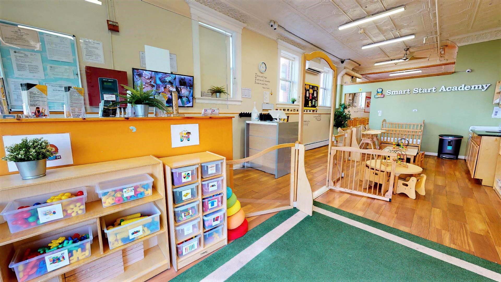 Toddler classroom lobby at Smart Start Academy with camera monitor and posted licensing