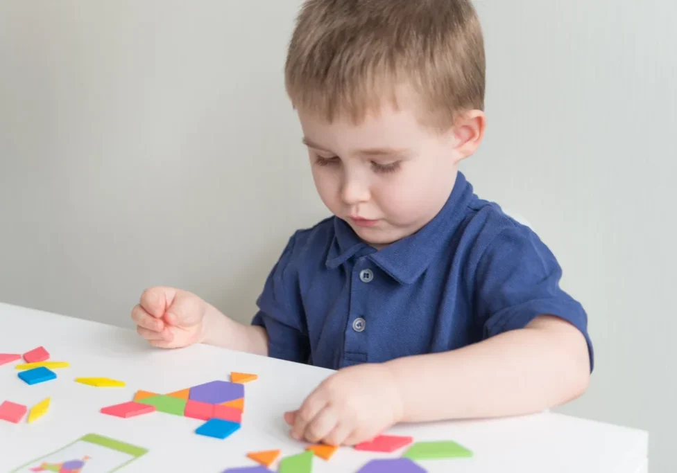 Child playing with colorful geometric puzzle pieces